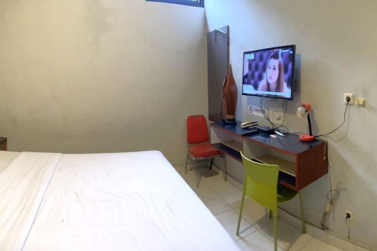 Une pièce comprenant un lit, un bureau avec un ordinateur, une chaise et un téléviseur.