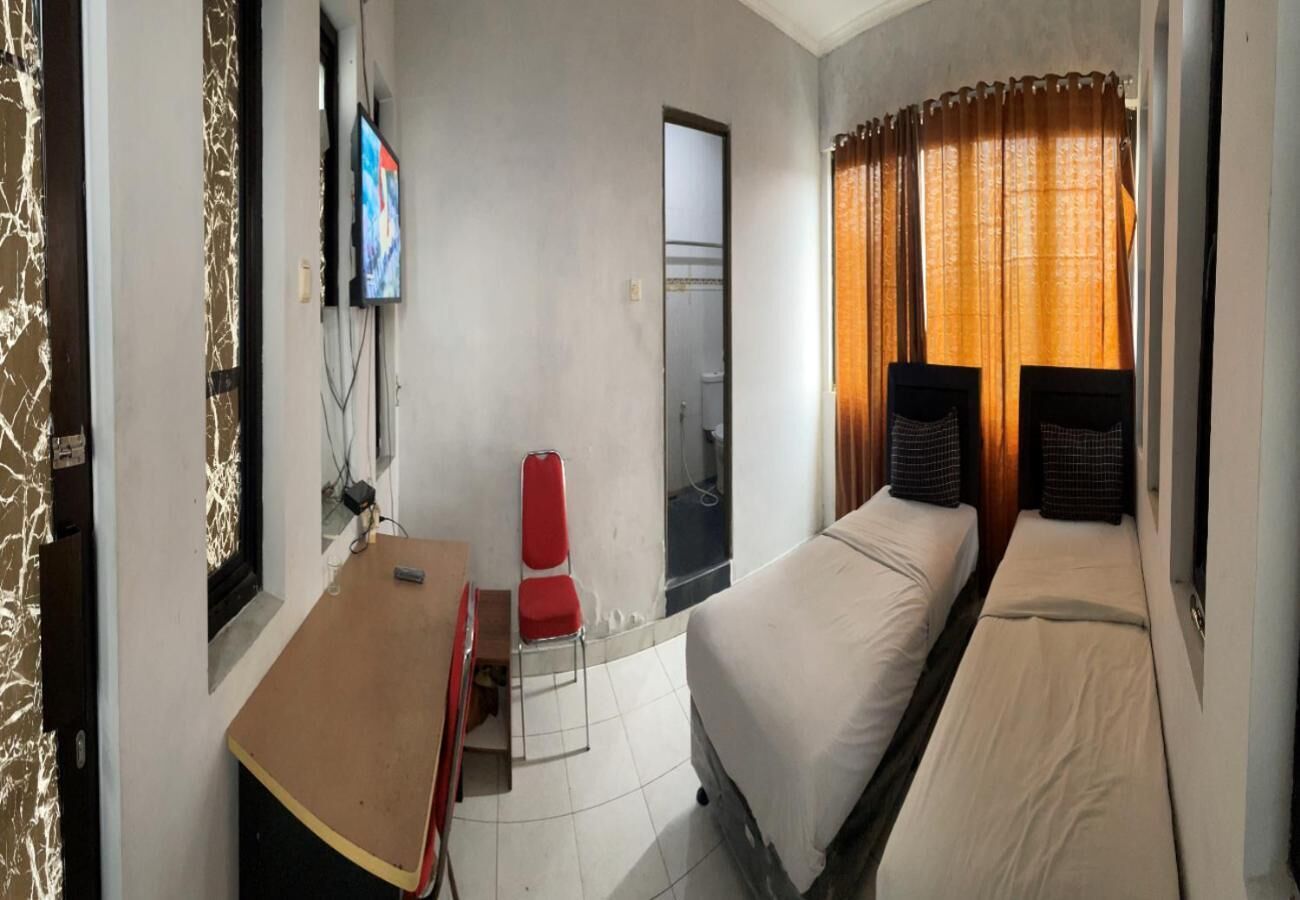 Una habitación de hotel con cama, escritorio, silla, televisor y ventana con cortinas.
