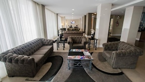 A spacious living room with a sectional sofa, two armchairs, a coffee table, and a television. - 3 Elegant Executive Rooms in Prime Location Steps from City’s Iconic Sights (Paraná)