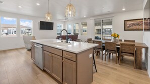 Une cuisine moderne dotée d’un îlot central, de meubles en bois et de luminaires suspendus.