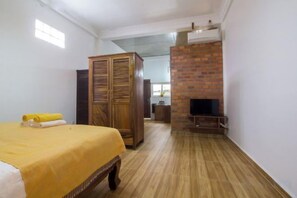 A room with a bed, wardrobe, TV, and a brick fireplace. - ANGKOR DINO HOME (Siem Reap)