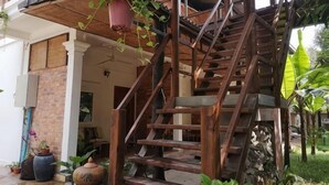 A wooden staircase leading to a covered area with potted plants and a brick wall. - ANGKOR DINO HOME (Siem Reap)