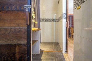 A bathroom with a wooden door, a shower area, and a tiled floor. - ANGKOR DINO HOME (Siem Reap)