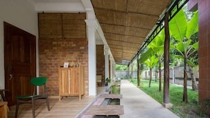 A covered corridor with a brick wall, a wooden cabinet, a chair, and a small water feature. - ANGKOR DINO HOME (Siem Reap)