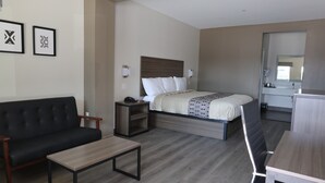 A hotel room with a bed, a sofa, a desk, and a mirror. - Hotel Royale (Houston)