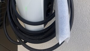 A Tesla charging station mounted on a textured wall. - Hotel Royale (Houston)