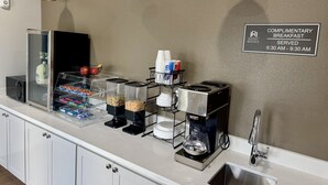 A complimentary breakfast area with a coffee machine, cereal, and snacks. - Hotel Royale (Houston)