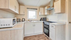 Une cuisine compacte avec des meubles blancs, un four à micro-ondes, un grille-pain, une bouilloire et une cuisinière.