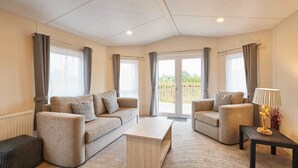 Un salon spacieux avec un canapé beige, une table basse et une petite table d’appoint sur laquelle se trouve une lampe.