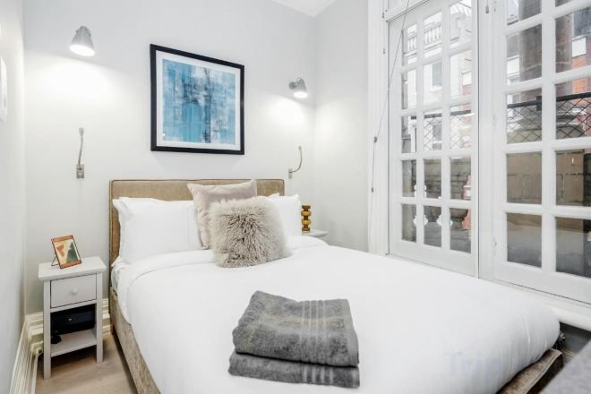 A hotel room with a bed, bedside tables, a framed picture on the wall, and a window with a view.