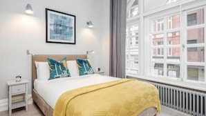 A bedroom with a bed, bedside tables, a window, and a radiator. - Kula London - Covent Garden St Martin's Lane (London)