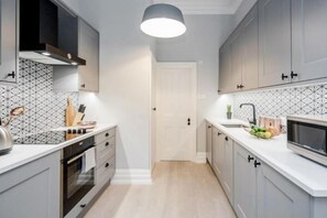 Una cocina moderna con armarios grises, una encimera blanca y una campana extractora negra.
