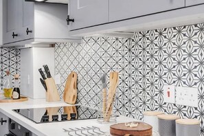Una cocina con salpicadero estampado, una estufa y utensilios de madera sobre la encimera.
