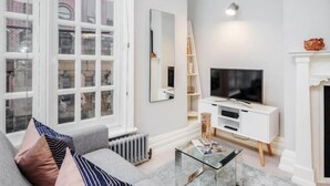 A modern living room with a large window, a fireplace, a TV, and a white cabinet. - Kula London - Covent Garden St Martin's Lane (London)