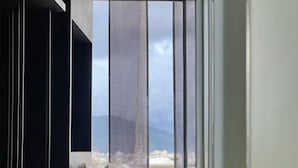 A room with a large window, a bed, and a view of a landscape. - Pause Apartment (Dalat)
