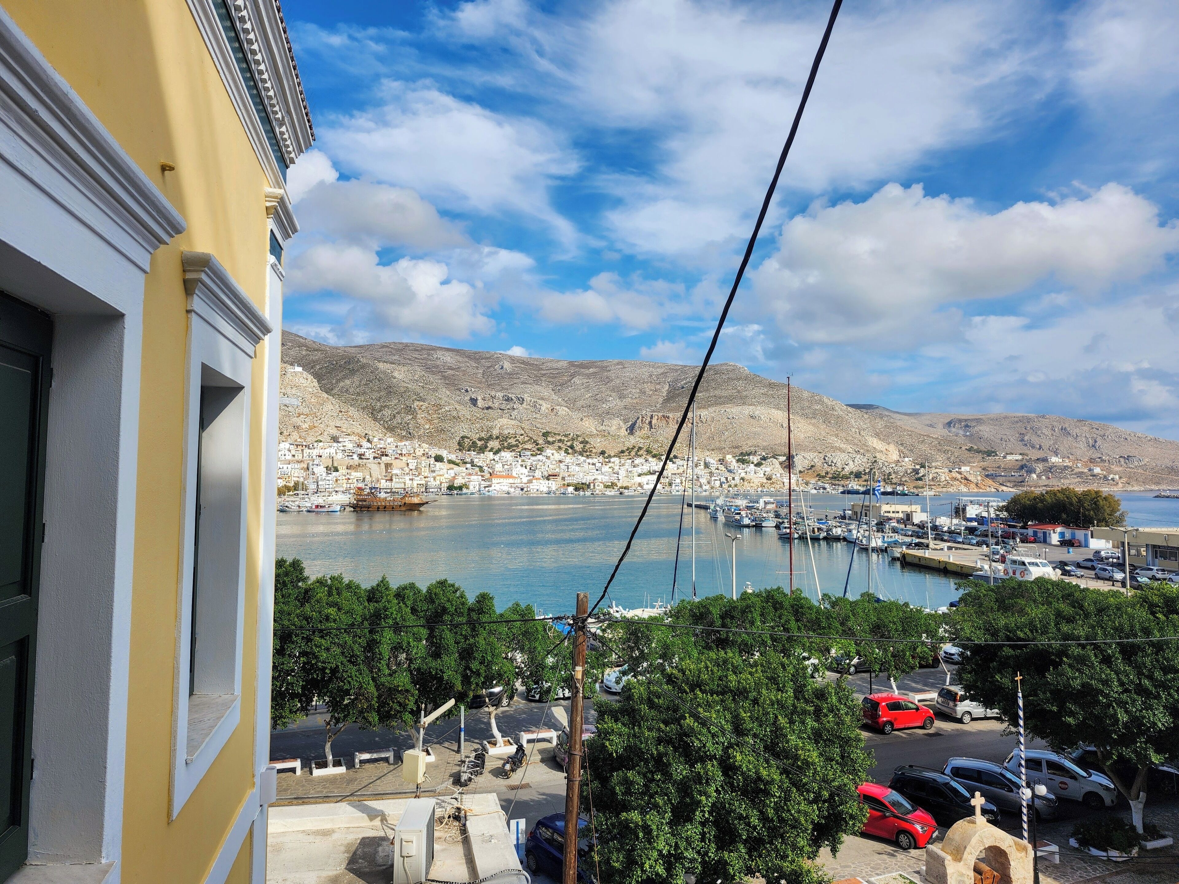 A coastal town with a marina, boats, and a mountainous backdrop.