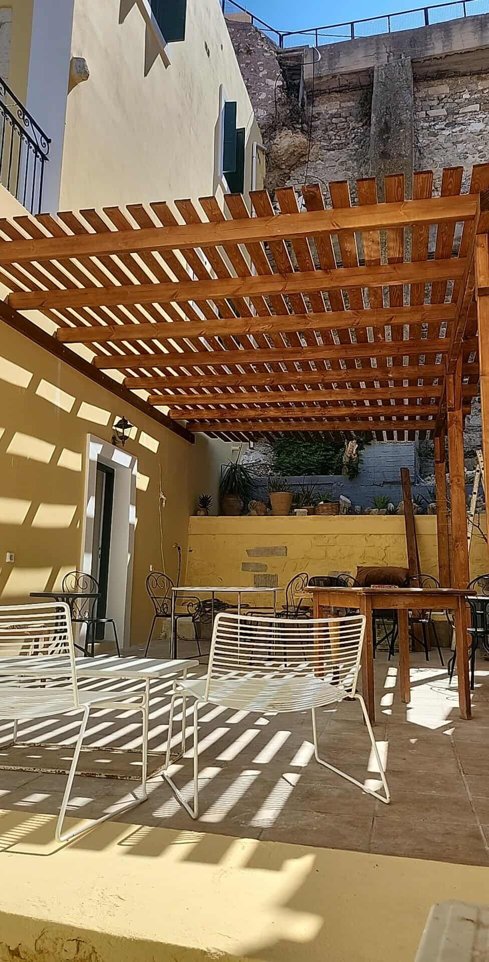 Eine Terrasse im Freien mit einer Holz-Pergola, Metallstühlen und -tischen.