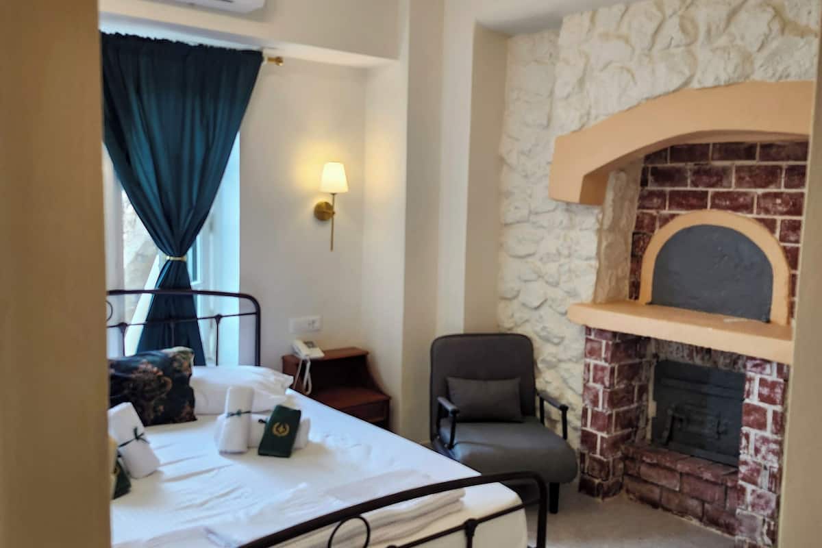 Un dormitorio con cama, una silla, una chimenea y una mesita de noche.