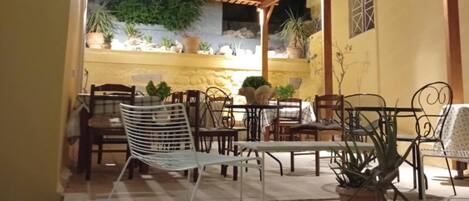 Un espace extérieur aménagé en terrasse, avec une pergola en bois, des tables, des chaises et des plantes en pot.