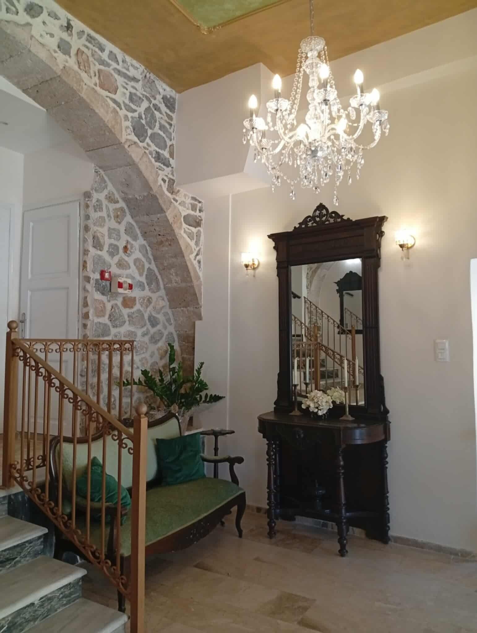 Un escalier avec un mur en pierre, une rampe en bois et un banc vert avec un coussin.