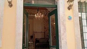 The entrance to Archontiko Hotel with a stone facade, green doors, and a chandelier. - Archontiko Hotel (Kalymnos)