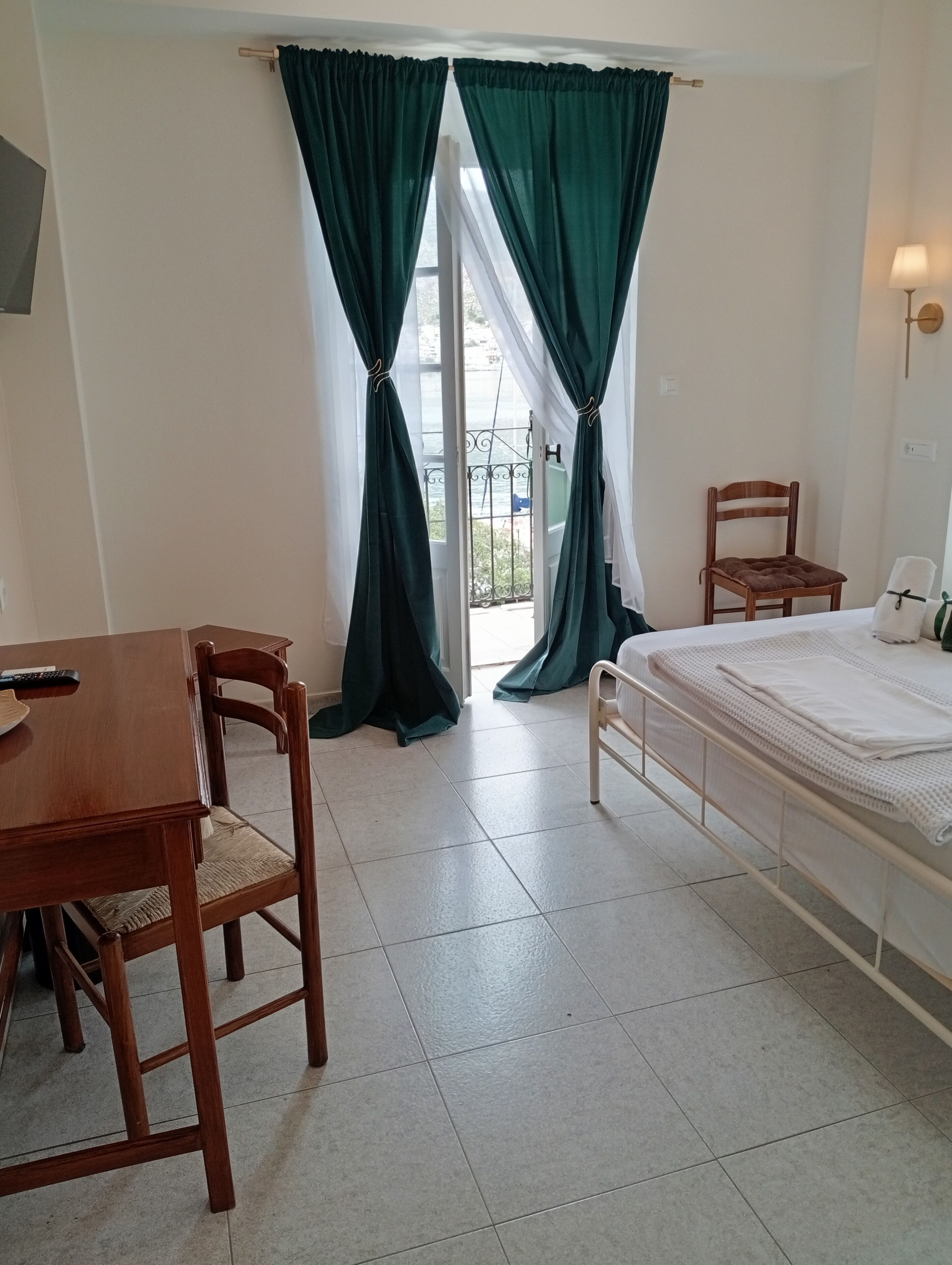 A room with a bed, a chair, a table, and a window with curtains.