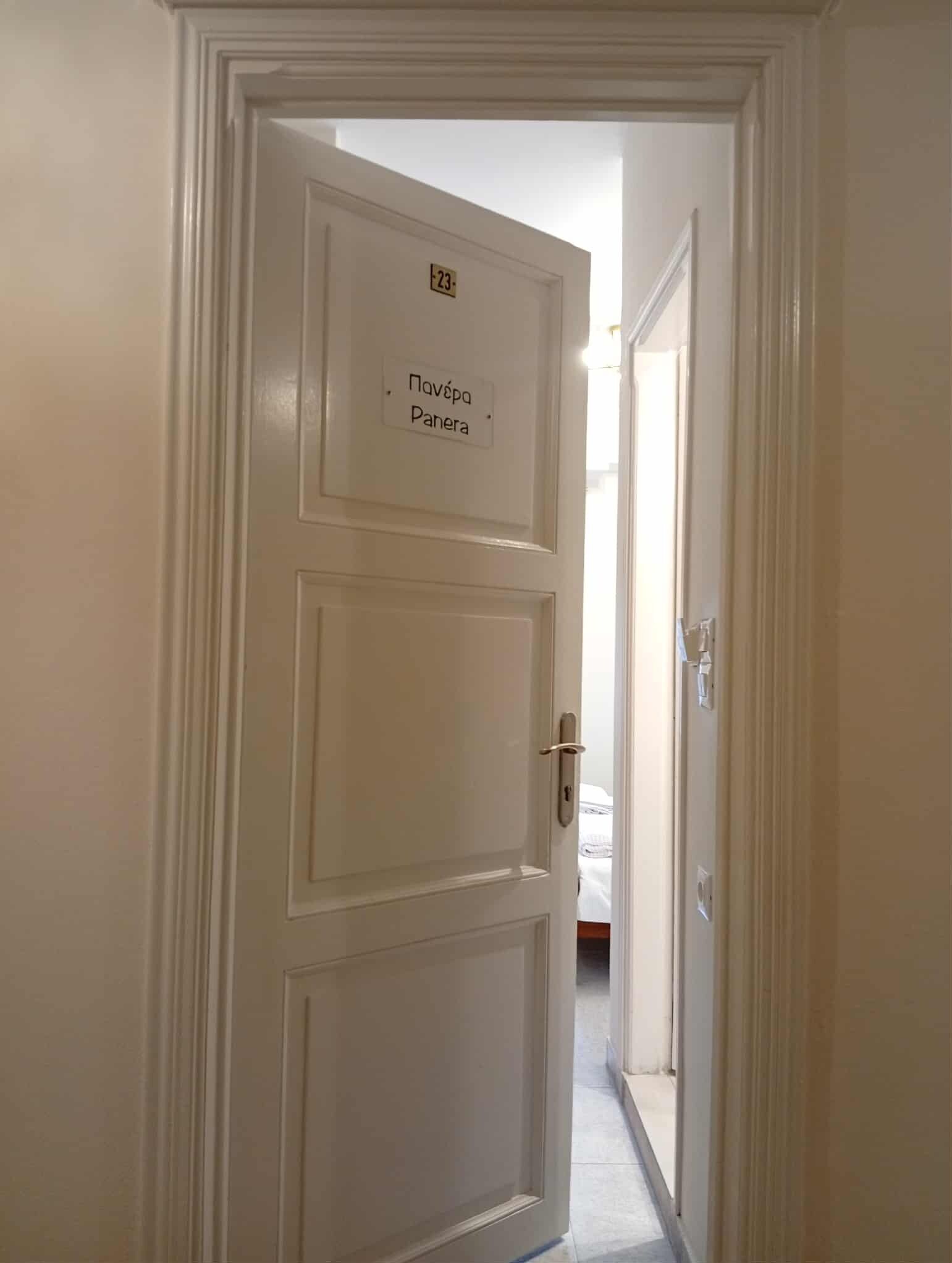 Une porte blanche avec une enseigne indiquant « Navèra Panera » et un trou de serrure.