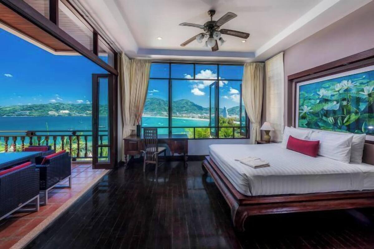 A hotel room with a bed, a desk, a chair, and a view of the ocean.