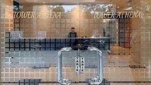 A hotel entrance with mirrored glass doors, a visible interior with a mannequin, and the name 'TOWER ATHENA' displayed on the glass.