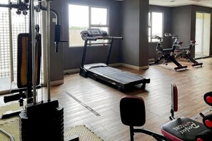 Une salle de sport équipée de tapis de course, de vélos d’appartement et de matériel de musculation.