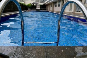 A swimming pool with a clear water surface and metal pool ladder. - Cozy & Modern Belmont Apt Studio w/ Wi-Fi &Netflix (West Jakarta)