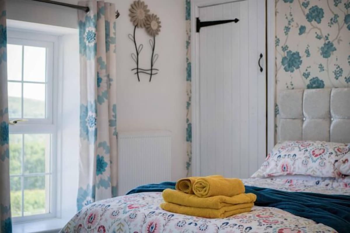 Ein Schlafzimmer mit Bett, Vorhängen, einem Heizkörper und einer Wanddekoration.