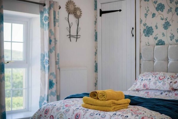 Ein Schlafzimmer mit Bett, Vorhängen, einem Heizkörper und einer Wanddekoration.