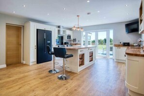 A modern kitchen with a central island, bar stools, and a large window.