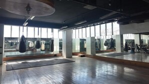A spacious gym with large windows, mirrors, and various exercise equipment. - Queensland Manor Condominium Deluxe Suite (Cebu City)