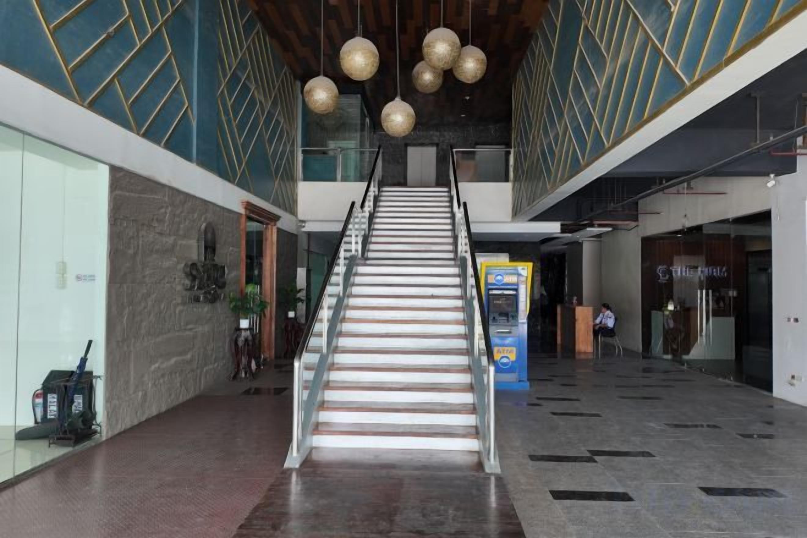 Een trap leidt naar een hoger gelegen verdieping in een gebouw met een modern design, inclusief geometrische patronen op de muren en hangende, sferische lampen.