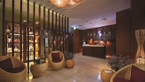 A modern spa reception area with a wooden reception desk, wicker chairs, and a decorative wall with shelves. - Landmark Center Saigon (Ho Chi Minh City)