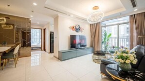 A modern living room with a black sofa, a glass coffee table, and a TV on a cabinet. - Landmark Center Saigon (Ho Chi Minh City)