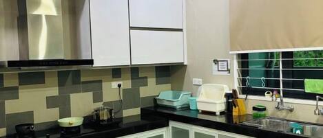 Una cocina moderna con armarios blancos, encimera negra y salpicadero de azulejos.