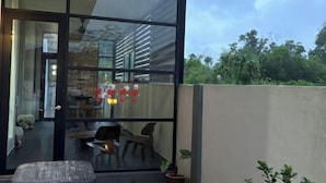 Ein modernes Zimmer mit einer großen Glasdoor, einer kleinen Sitzecke und Blick ins Freie.