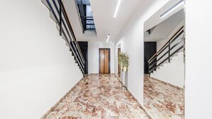 Un interior moderno con suelo de mármol, una escalera y una puerta que da a otra habitación.