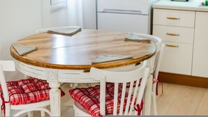 Una mesa redonda de madera con sillas blancas, cada una con cojines a cuadros blancos y rojos.