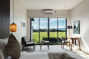 Un dormitorio moderno con una ventana grande, una cama, un escritorio y una silla.
