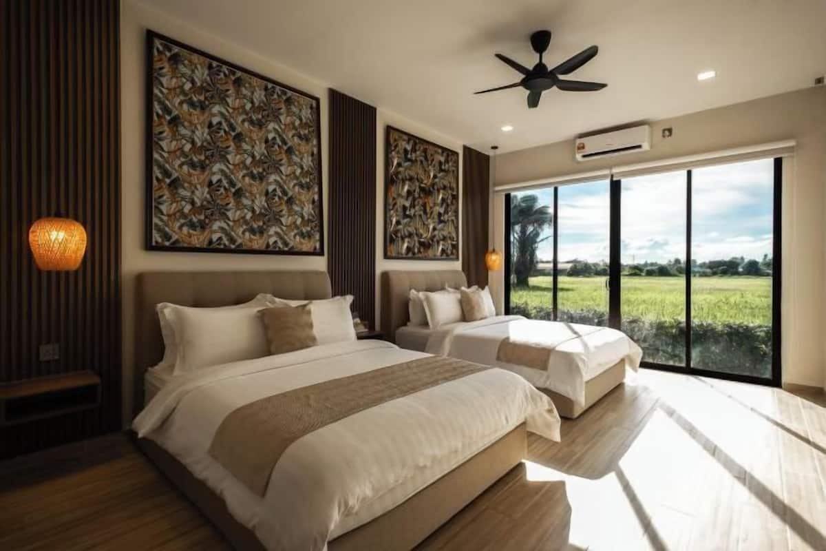 A modern bedroom with two beds, large windows, ceiling fan, and artwork on the walls.