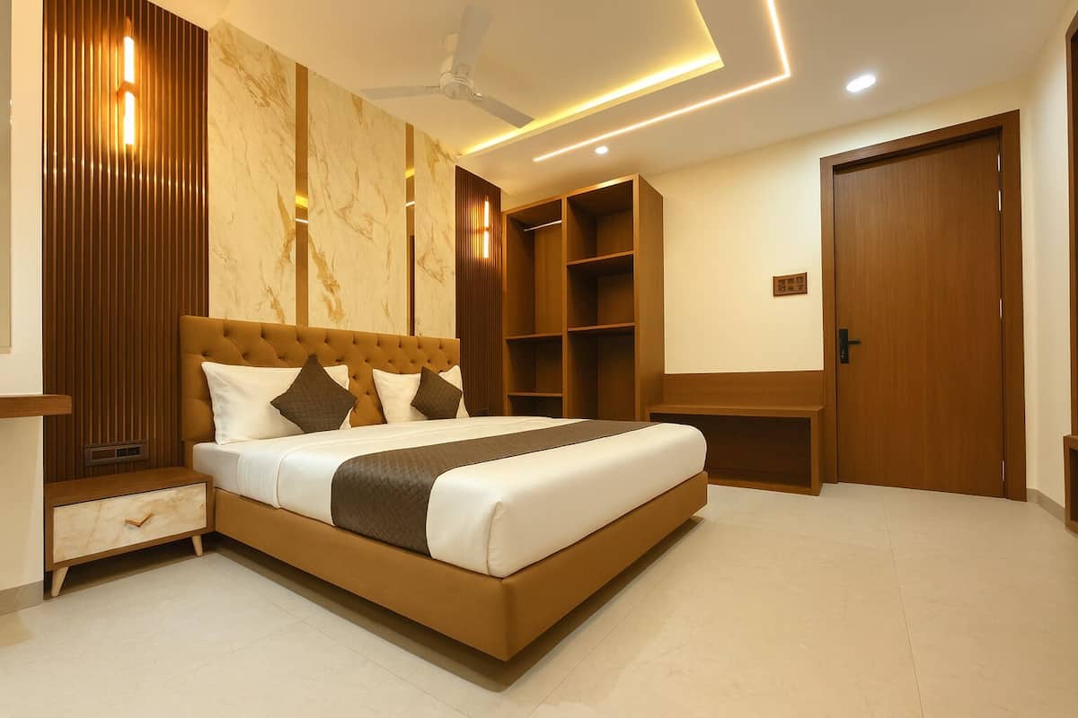 A modern bedroom with a large bed, built-in wooden shelving, and a ceiling fan.