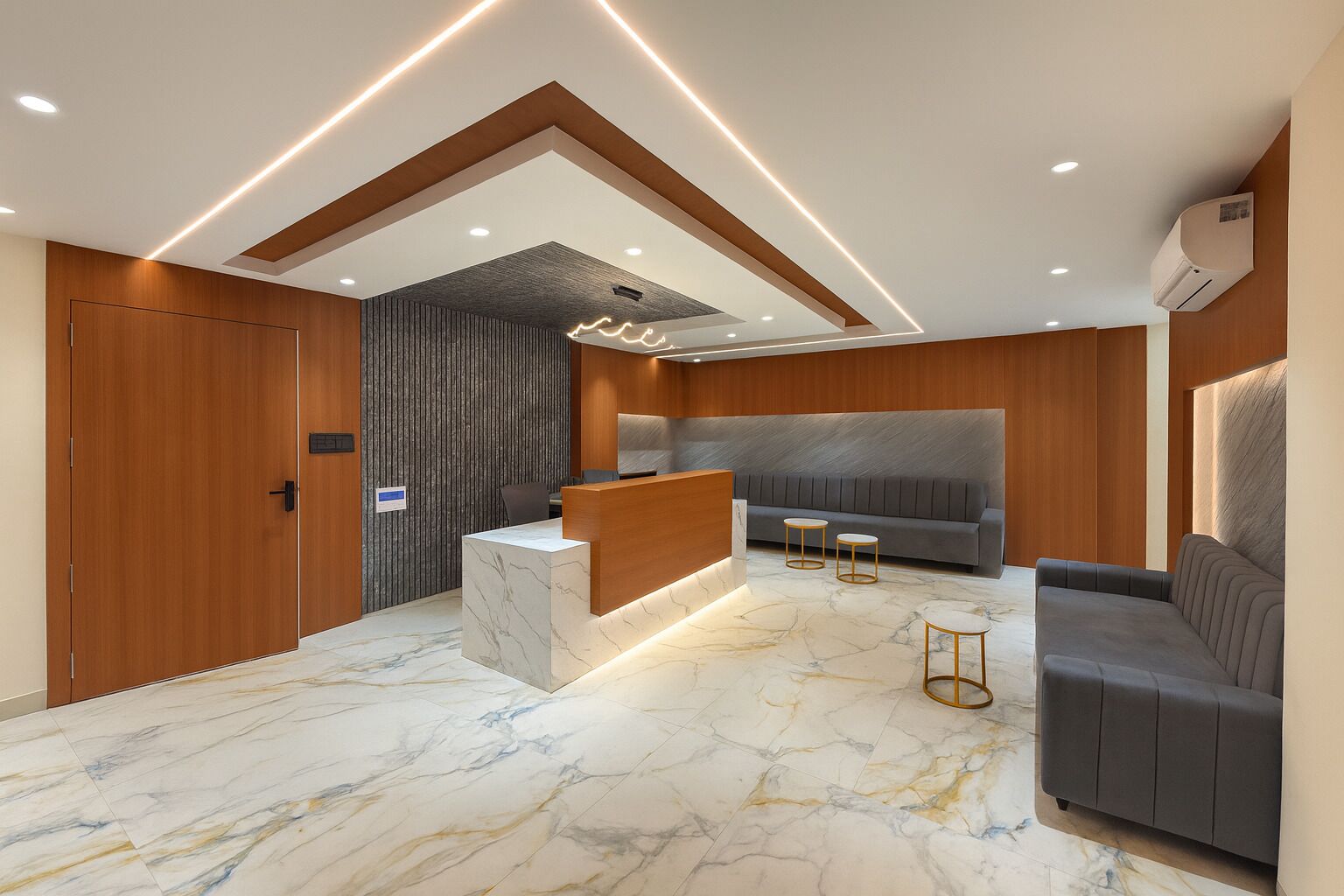 A modern reception area with a marble floor, wooden accents, a reception desk, a sofa, and two small tables.