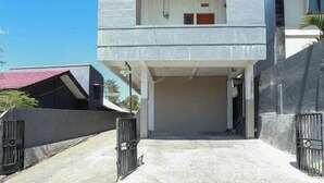 A two-story building with a covered entrance and a gated driveway. - Citra Homestay Soe (Soe City)