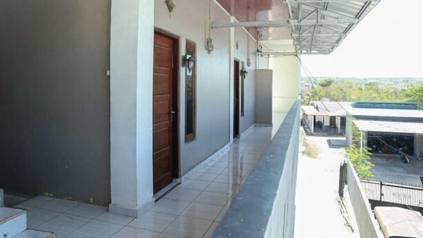 A covered corridor with doors, a tiled floor, and a view of the surrounding area. - Citra Homestay Soe (Soe City)