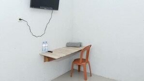 A corner room with a desk, chair, and a TV mounted on the wall. - Citra Homestay Soe (Soe City)