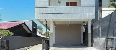 A two-story building with a covered entrance and a gated driveway.